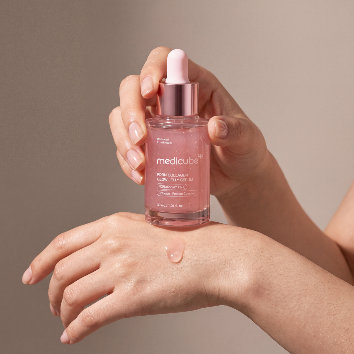 Medicube PDRN Pink Collagen Glow Jelly Serum held in hands, editorial studio shot