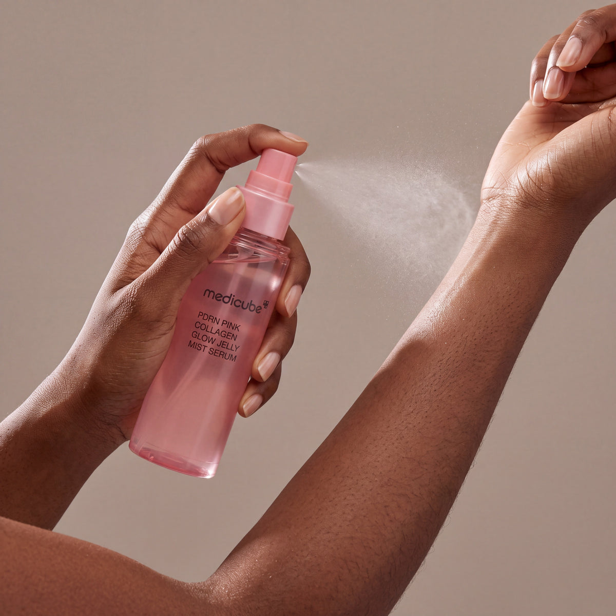 Medicube PDRN Pink Collagen Glow Jelly Mist Serum held in hands, editorial studio shot