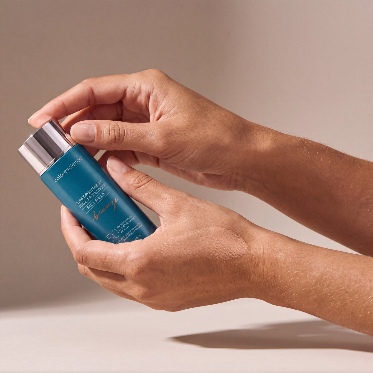 Colorescience Sunforgettable Total Protection Face Shield Bronze SPF 50 held in hands, editorial studio shot