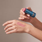 Colorescience Colour Balm Berry held in hands, editorial studio shot
