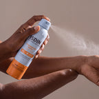 Isdin Transparent Spray held in hands, editorial studio shot