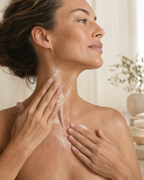 Woman smoothing cream upward along her neck and décolletage